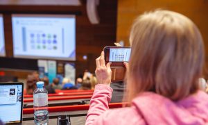 Udeleženka foruma fotografira predstavitev